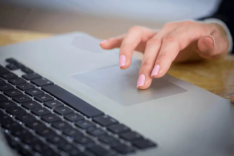 Hand hovering over a laptop trackpad with a website and its banner open on screen
