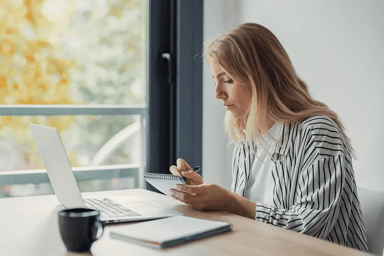 Person reviewing a checklist on a laptop by a window