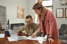 Two people comparing documents at an office desk