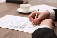 Close up of a contract being signed with a pen on a desk