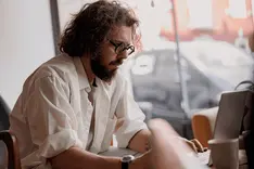 Business owner at a laptop in a café calculating the cost of a hire, a freelancer and the Illia BizTech team on a tariff