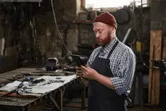 Tradesperson checking a smartphone at the workshop bench