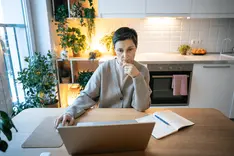 Person checking email inbox on a laptop at the kitchen table in the morning